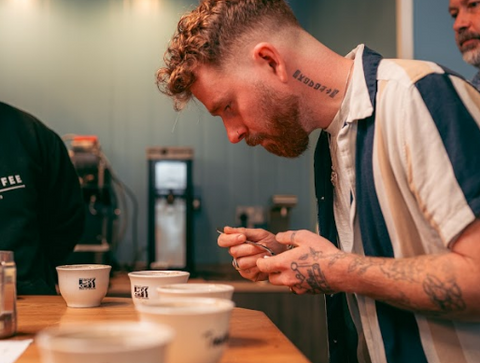 A handsome man trying coffee during a "coffee cupping" or coffee tasting.