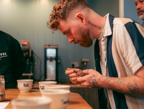 A handsome man trying coffee during a "coffee cupping" or coffee tasting. 