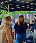 Woman in a blue shirt and sunglasses teaching latteart to customers